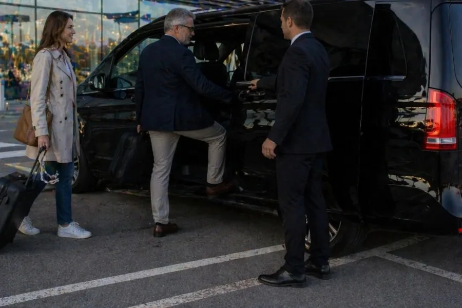 Passeggeri con le valigie salgono su un minivan Mercedes nero in aeroporto