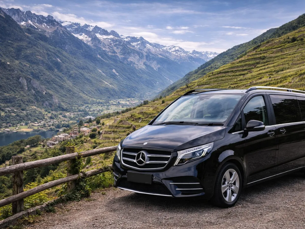 Valtellina wine tour: black Mercedes minivan on a road among the terraced vineyards