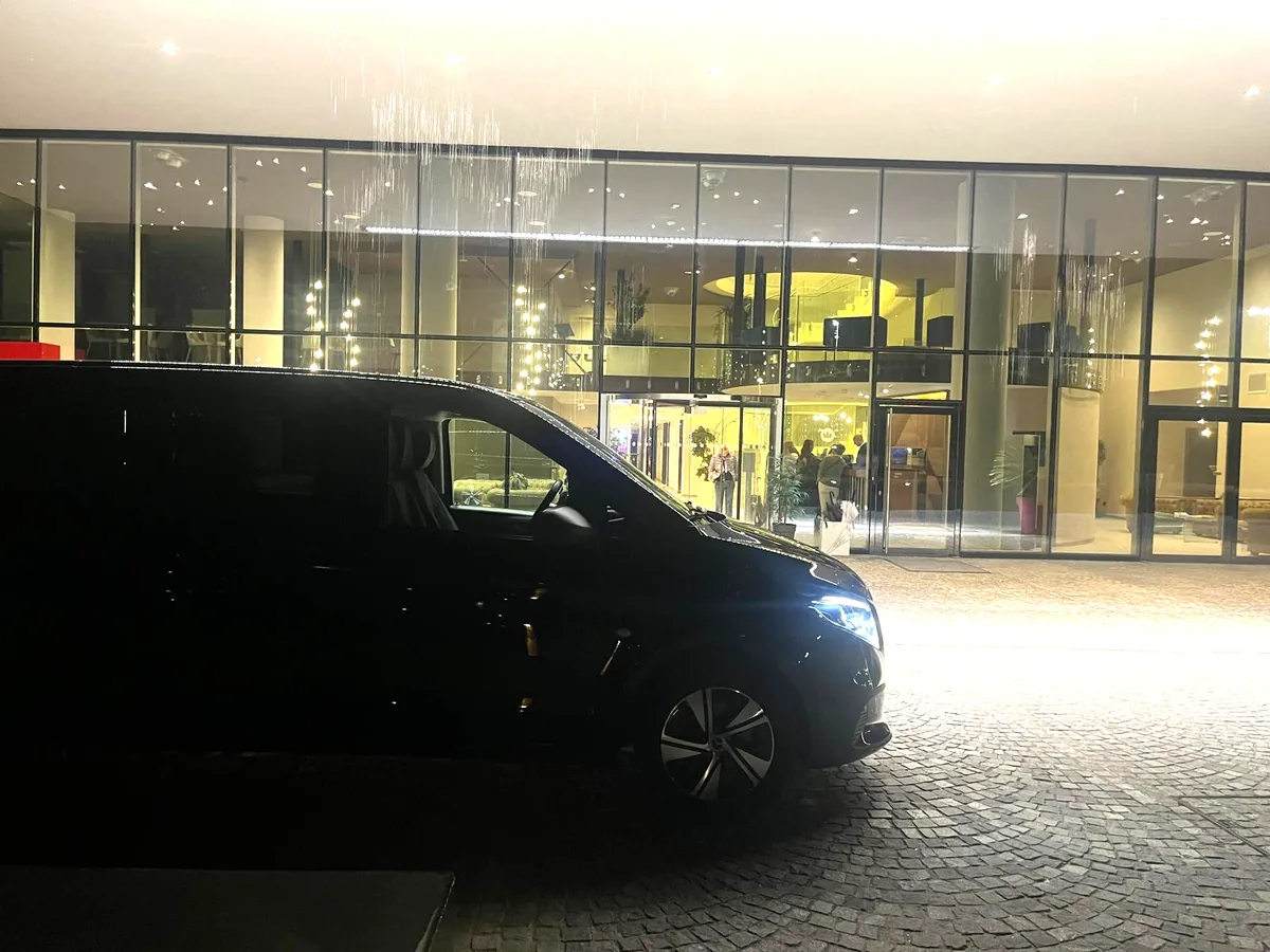 Minivan Mercedes nero in attesa davanti all'ingresso di un hotel, di sera