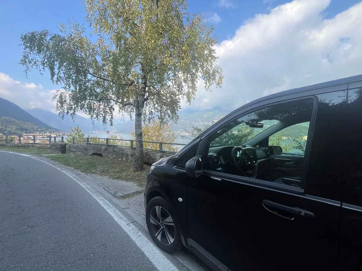 Lake Como to Venice private transfer: black Mercedes minivan on a road above the lake